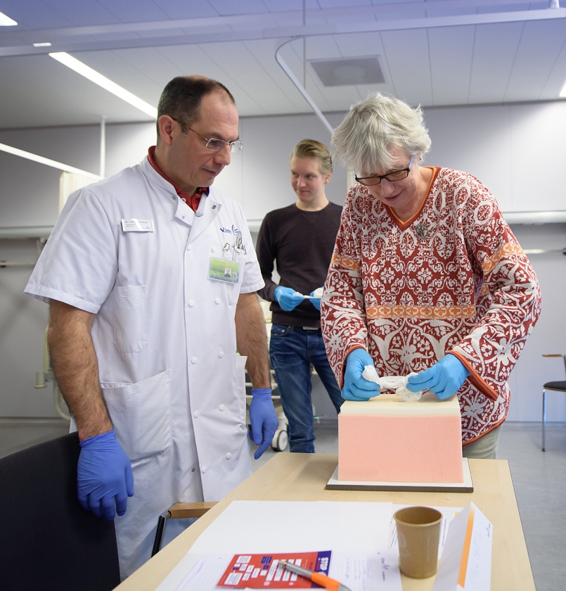 Traumachirurg Leo Geeraedts kijkt toe hoe een cursist een ‘oefenwond’ opstopt met gaasverband. (fotografie vumc, Hans Smit)