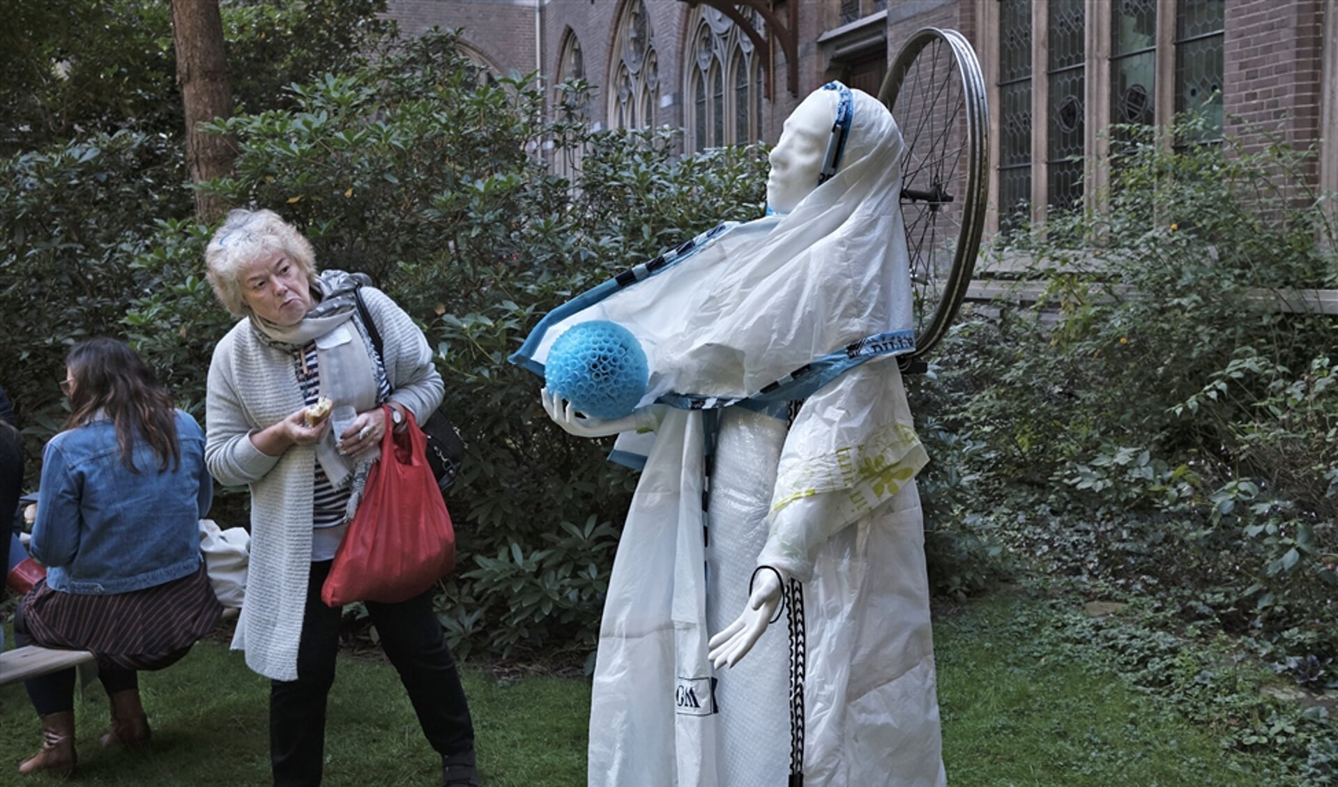 Een bezoeker bekijkt de Klimaatmadonna in de stiltetuin van het Dominicanenklooster in Zwolle. Dit beeld van Maria is door kunstenares Marit Otto gemaakt van afval dat afkomstig is van de kloostergemeenschap en de buurtbewoners.