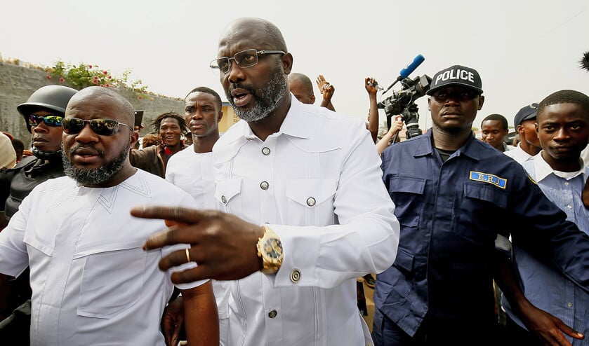 George Weah (m.) verlaat onder bewaking het stembureau in Monrovia waar hij kort tevoren zijn stem heeft uitgebracht in de tweede ronde van de Liberiaanse presidentsverkiezingen. (epa / Ahmed Jallanzo)