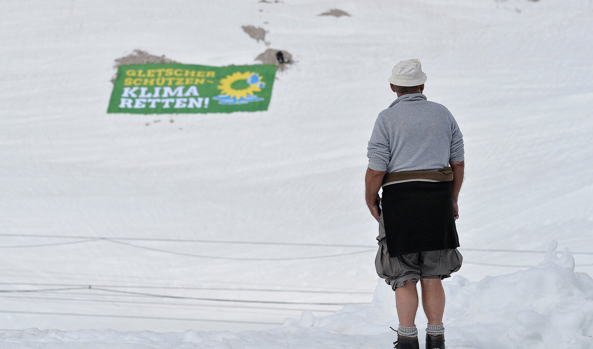 Een toerist leest een banner van de Duitse Grünen, waarin wordt opgeroepen gletsjers te beschermen.