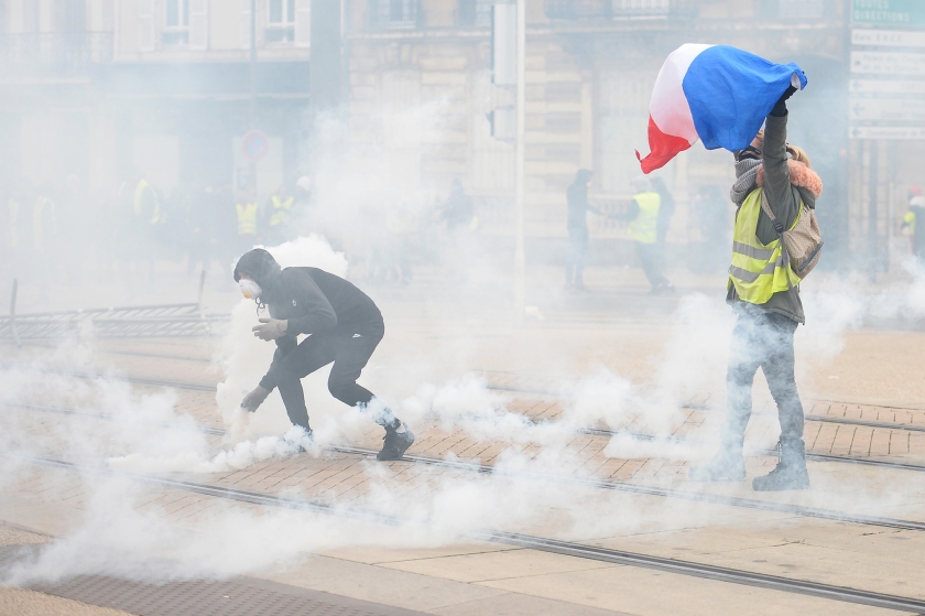 Een demonstrant van de zogenoemde gelehesjesbeweging gooit een traangasgranaat terug naar de politie in het Franse Le Mans. Ondanks het ‘grand débat national’ van president Macron houdt in veel steden de onrust aan. (afp / Jean-François Monier en nd)