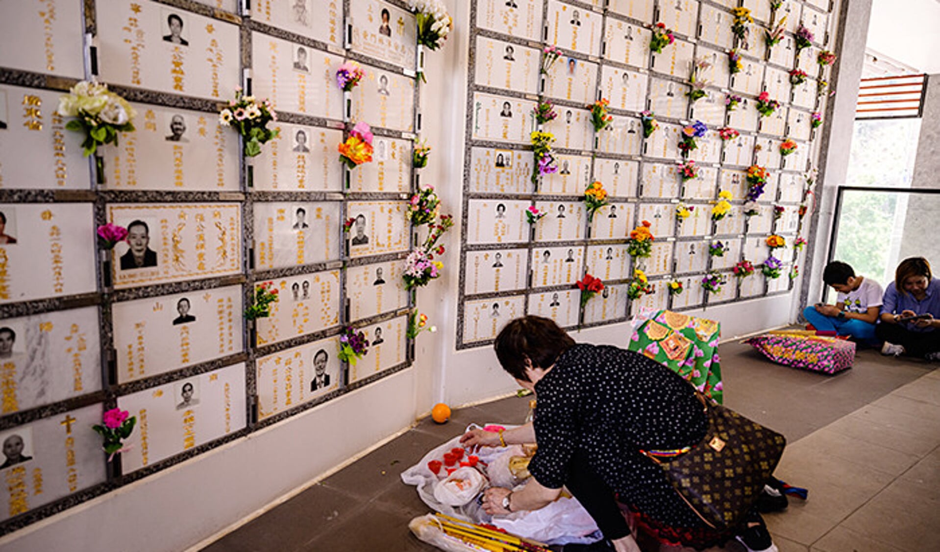 Een vrouw laat offergaven voor haar voorouders achter bij een columbarium in Hongkong.
