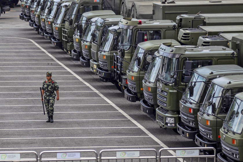 Een militair van het Chinese Volksleger loopt donderdag langs militaire vrachtwagens in een sportstadion in Shenzhen.  (epa / Alex Plavevski)