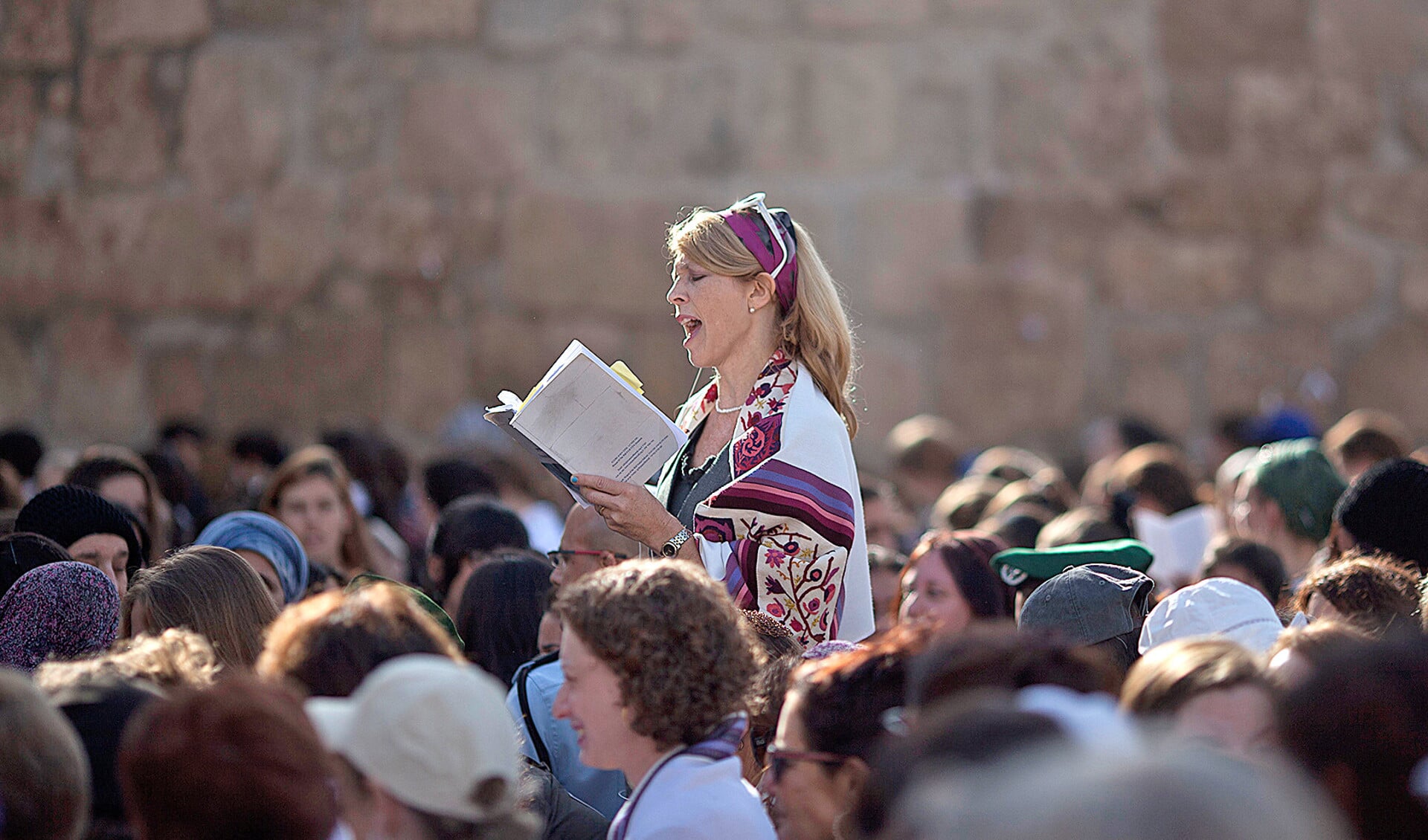 Een joodse vrouw met een gebedsmantel om bidt hardop bij de Klaagmuur in Jeruzalem. Orthodoxe joden zijn van mening dat dit in strijd is met de joodse wetgeving.