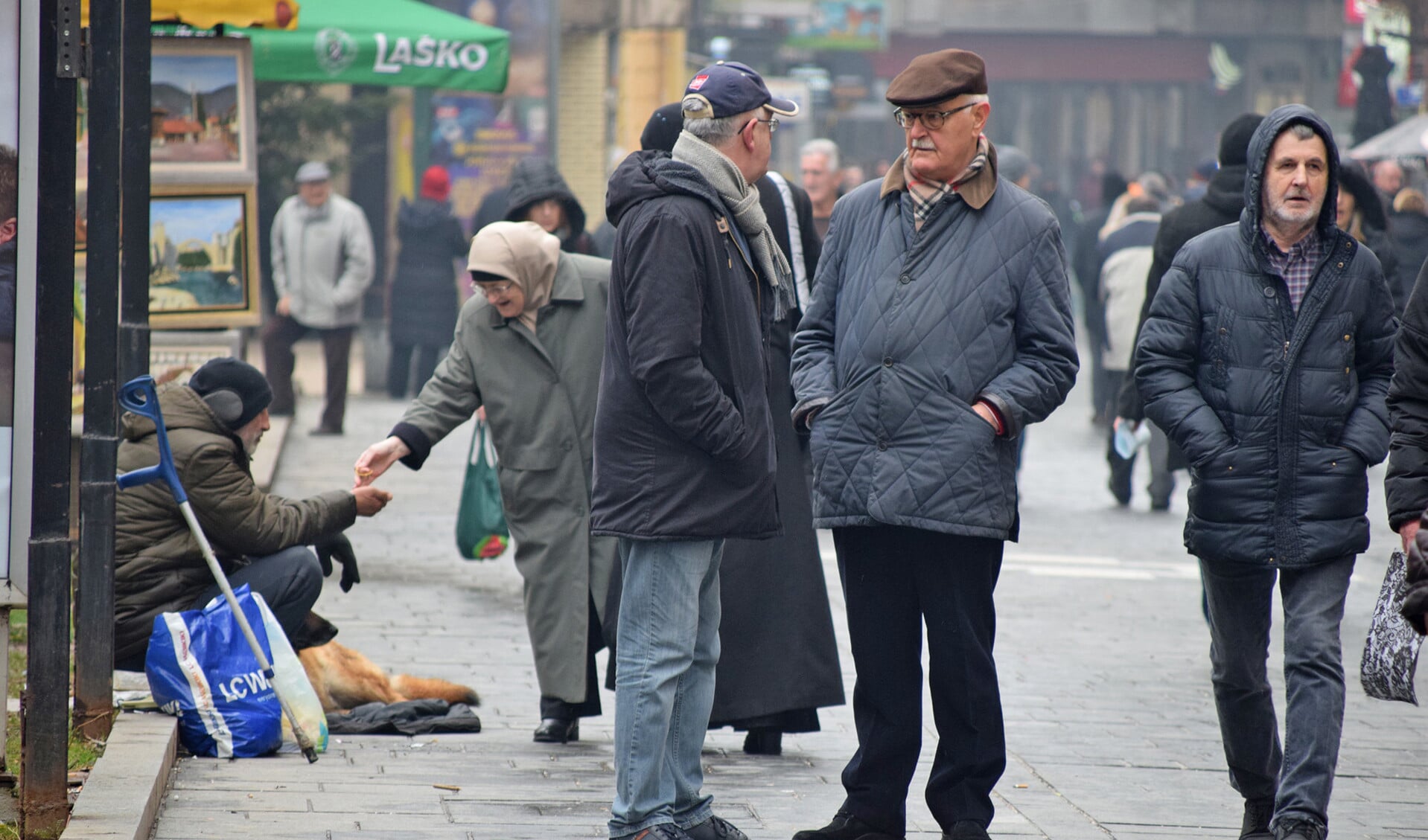 Een voorbijgangster geeft een paar muntjes aan een bedelaar in Sarajevo, de hoofdstad van Bosnië-Herzegovina.
