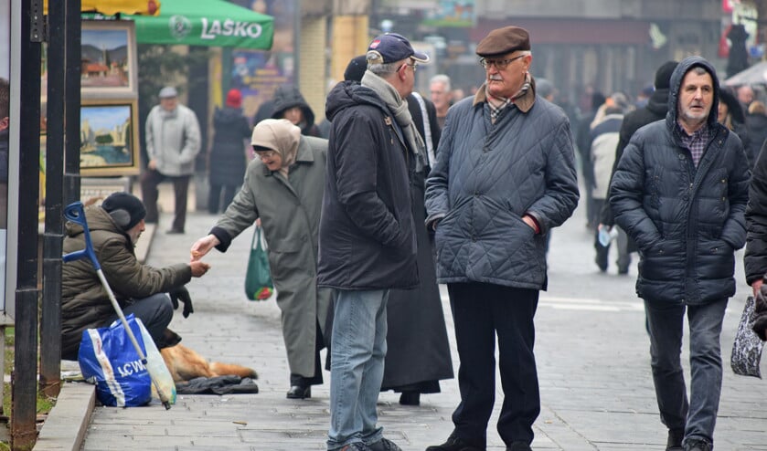 Een voorbijgangster geeft een paar muntjes aan een bedelaar in Sarajevo, de hoofdstad van Bosnië-Herzegovina. (Marjolein Koster)