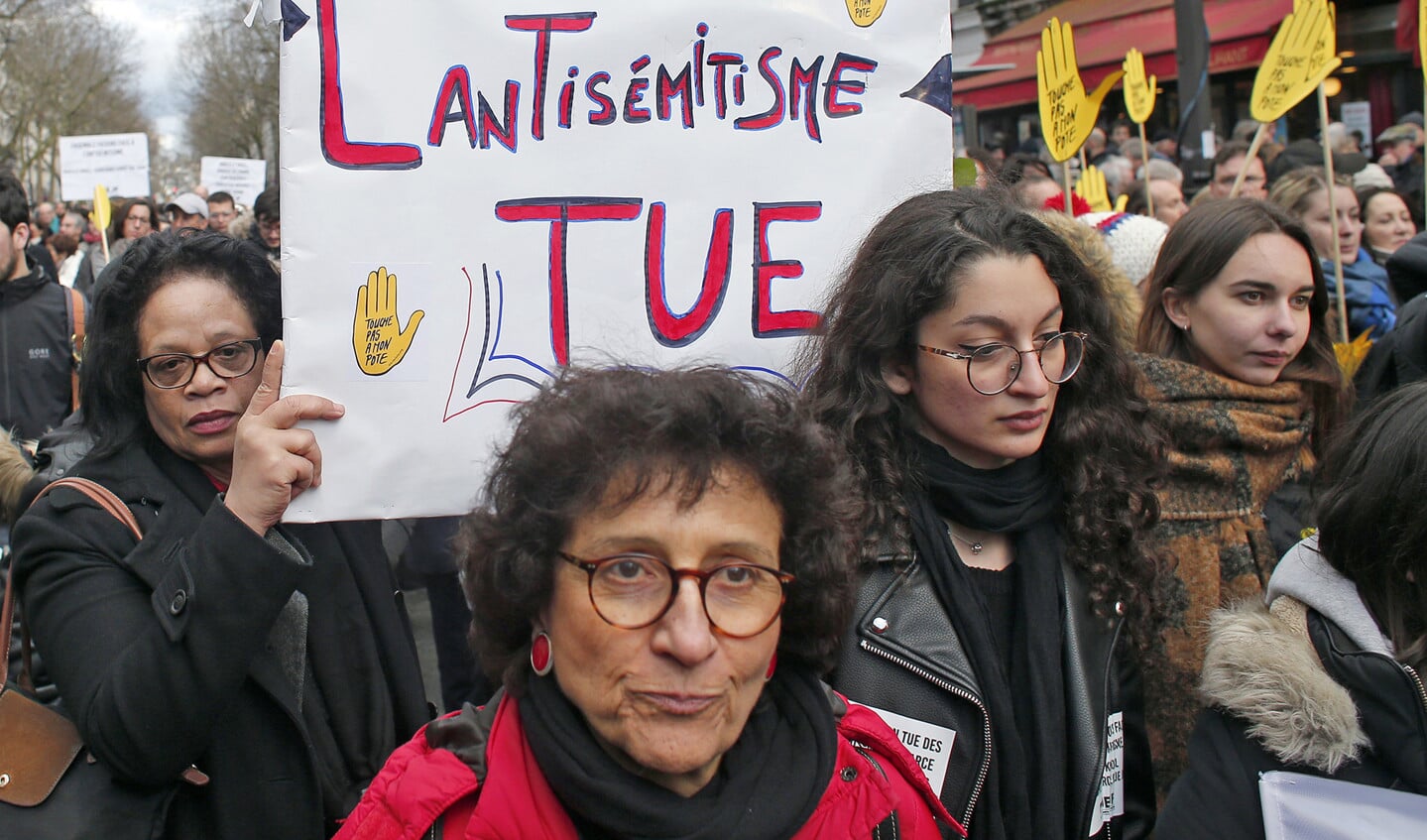 Een Franse vrouw die meeloopt in een stille mars om Mireille Knoll te gedenken, houdt een bord omhoog met de tekst: ‘Antisemitisme is dodelijk’.