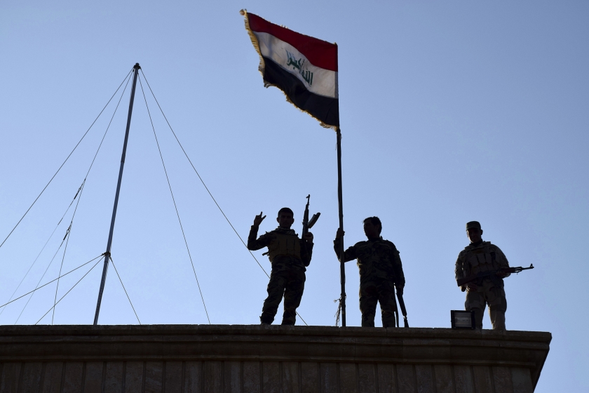 Soldaten planten de Iraakse vlag op een overheidsgebouw in Ramadi. De Iraakse troepen veroveren de stad op ISIS. (ap)
