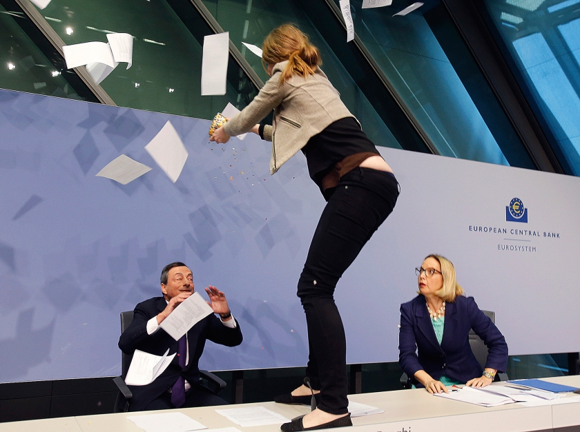 Een demonstrant sprong 15 april van dit jaar tijdens een persconferentie van Draghi in Frankfurt op de tafel. Ze maakte deel uit van een protestgroep die de Europese Centrale Bank dictatoriale trekken verwijt. (ap / Michael Probst)