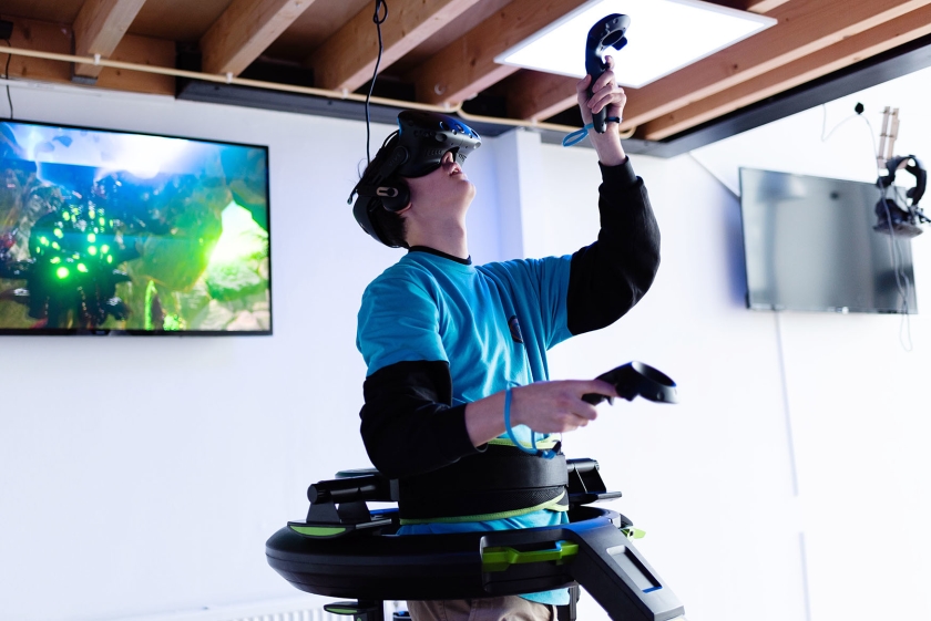 Een bezoeker van Virtuality in Amsterdam schiet op monsters in een game op de Virtuix Omni, een installatie voor virtual reality met ingebouwde loopband. (Katja Poelwijk)