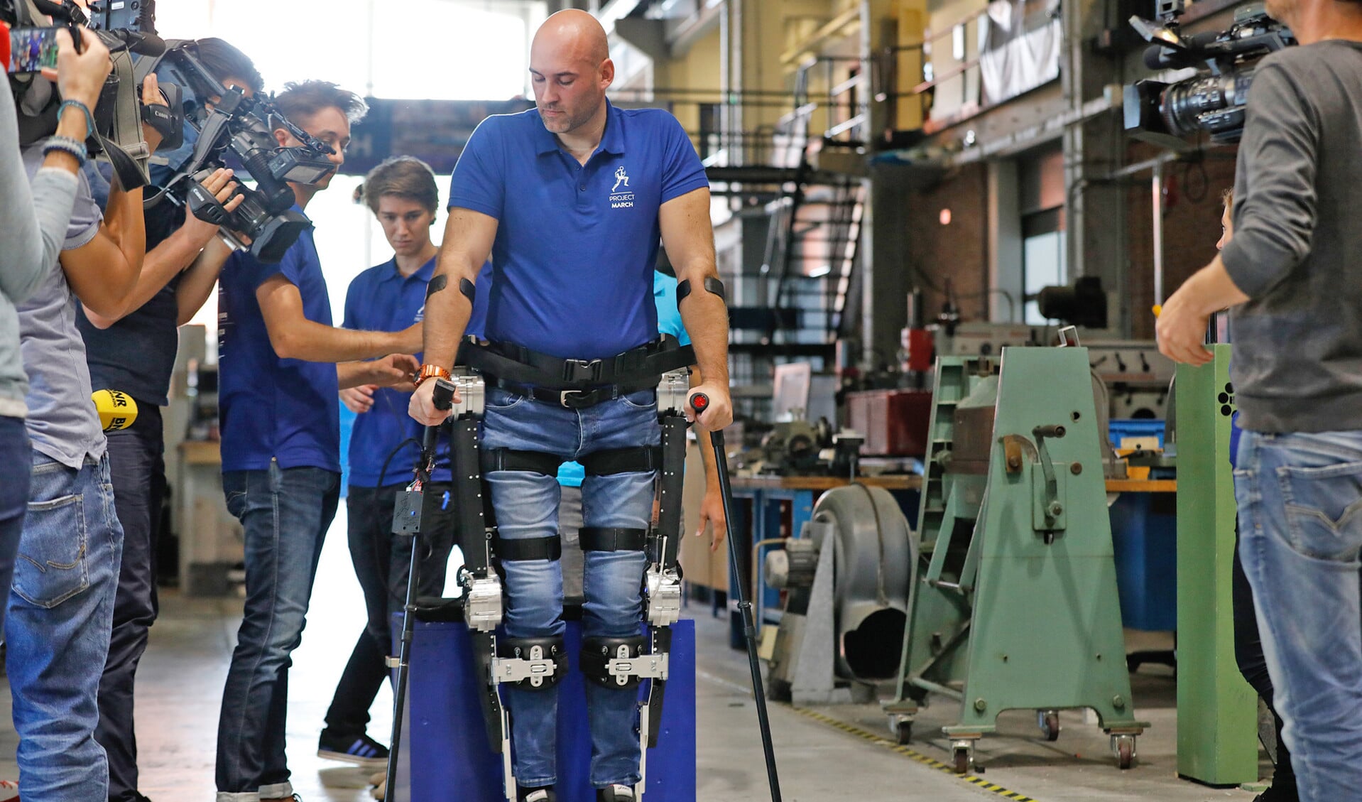 Laten we het woord ‘gehandicapten’ nooit meer gebruiken. Wij mensen zijn allemáál beperkt. Op de foto: dwarslaesiepatient Ruben de Sain zet de eerste stappen in het exoskelet van de TU Delft. Het ondersteunend robotisch pak is ontwikkeld door een team studenten.