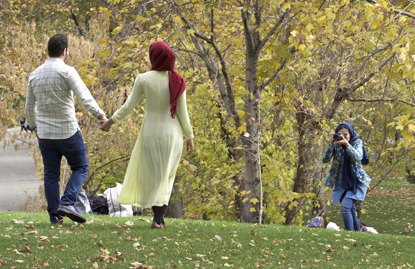 Een jong Iraans stel laat zich fotograferen in een park in Teheran. De vrouw voldoet niet aan de in Iran geldende kledingeisen. Ze heeft wel het haar bedekt met een hoofddoek, maar haar lichaamsvormen zijn goed zichtbaar. (ap / Jochen Eckel)