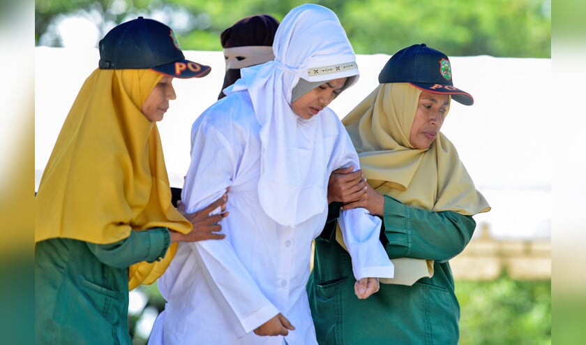 2018-10-29 07:09:22 Sharia police officers escort a 21-year old Muslim woman (C) for public caning after being caught in close proximity with her boyfriend in Banda Aceh on October 29, 2018. Aceh is the only province in the world’s most populous Muslim-majority country that imposes sharia law and people can be flogged for a range of offences -- from gambling, to drinking alcohol to having gay sex or relations outside of marriage. (afp en anp / Robin van Lonkhuijssen)