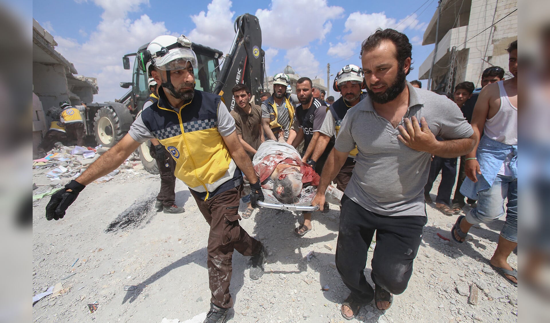 Burgers en leden van de Syrische Civiele Bescherming, ook bekend als de ‘Witte Helmen’, dragen een gewonde weg na een luchtaanval, dinsdag, door Syrische regeringskrachten bij Maaret al-Numan, in Noordwest-Syrië.