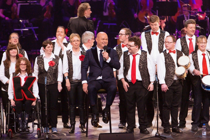 Leden van het APK-koor op het podium van theater Carré tijdens het Knoop Gala afgelopen zaterdag, met presentator Paul de Leeuw. APK staat voor Alkmaars Prachtkoor. (ntr)