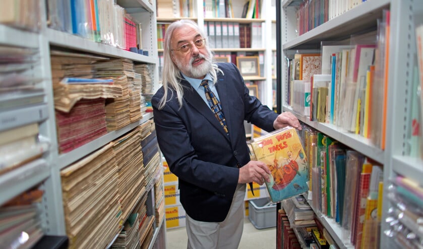 Hans Matla, uitgever, verzamelaar en auteur van de Stripkatalogus tussen 600 strekkende meter boekenplank. (Ton Koene)