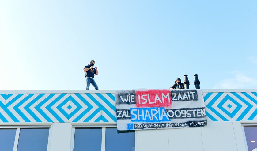 Twee mannnen hingen maandag een spandoek aan de gevel van de nieuwe islamitische middelbare school in Amsterdam. (anp / ginopress)