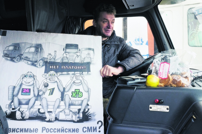Joeri Michajlov in zijn Volvo. De horen-zien-zwijgenaapjes op de poster staan voor de grote staatszenders (Rossija 24, Eerste Kanaal, NTV), die het protest allemaal negeren. Daaronder staat: ‘Onafhankelijke Russische media?’ Op het spandoek: ‘Nee tegen Platon’. (Arthur Bondar)