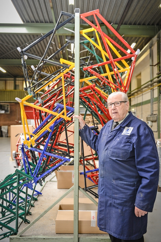 De 93-jarige Henk Kluver bij een stapel fietsenframes in de productiehal van Van Raam. (Van Raam)