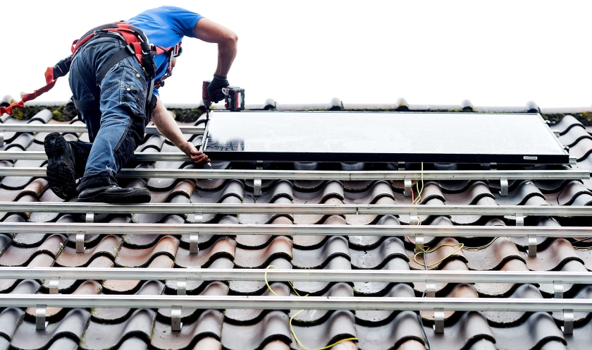 Een monteur plaatst zonnepanelen op het dak van een woonhuis. Aanbieders verwachten dat er dit jaar 7 miljoen panelen bijkomen. (anp / Koen van Weel)