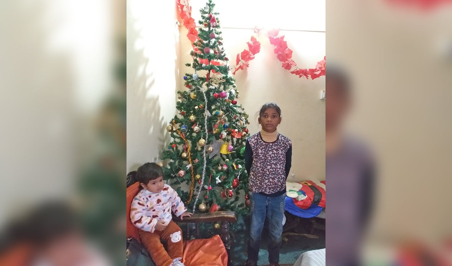 Twee van de kinderen van Cornelius en Roshanna. De ouders werken dag en nacht voor hun opleiding. Het meisje naast de kerstboom wil dokter worden.