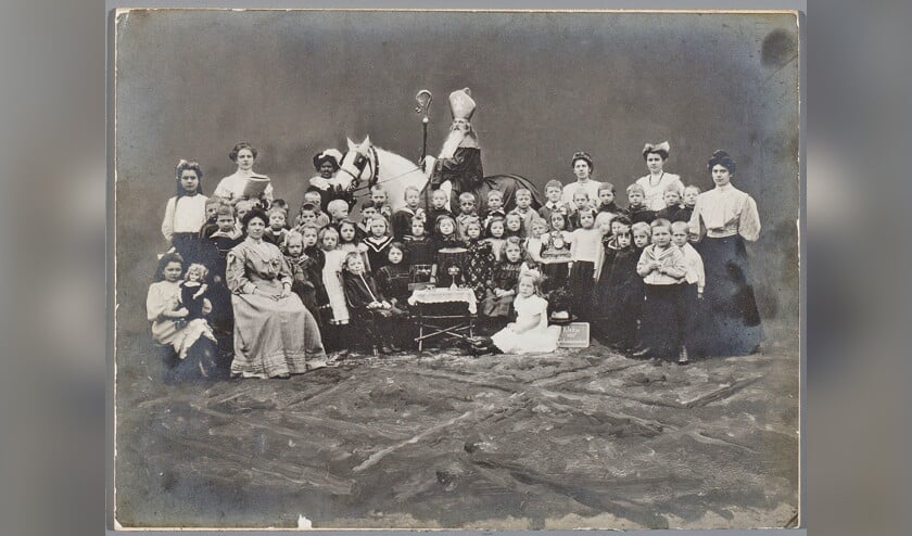 Sint-Nicolaas en Zwarte Piet op bezoek bij de kinderen van de bewaarschool aan de Doelenstraat in Alkmaar in 1908. (C. van der Aa / Archief Alkmaar)