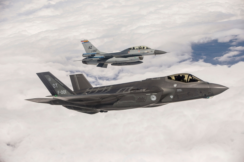 De eerste Nederlandse F-35 (F-001) vliegt boven Edwards Air Force Base, geflankeerd door een F-16. (Mediacentrum Defensie)