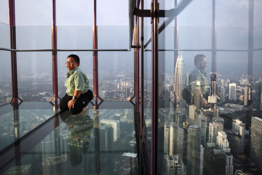 Een jongen laat zich in de Kuala Lumpur Tower in Maleisië op de foto zetten, met op de achtergrond de Petronas Twin Towers. De Petronas Twin Towers was bij de inwijding in 1998 het hoogste gebouw ter wereld (ap / Joshua Paul)