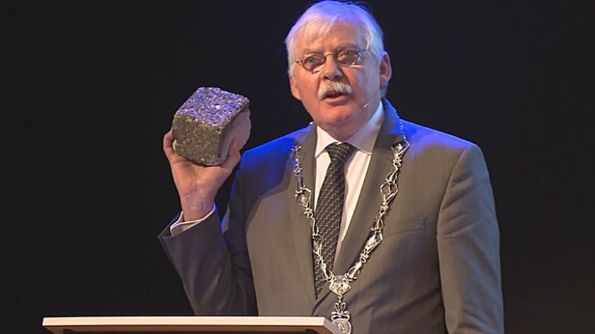Burgemeester Cees van der Knaap van Ede laat de steen zien waarmee de politieauto waarin hij tijdens Oud en Nieuw zat, werd bekogeld. (omroep gelderland)