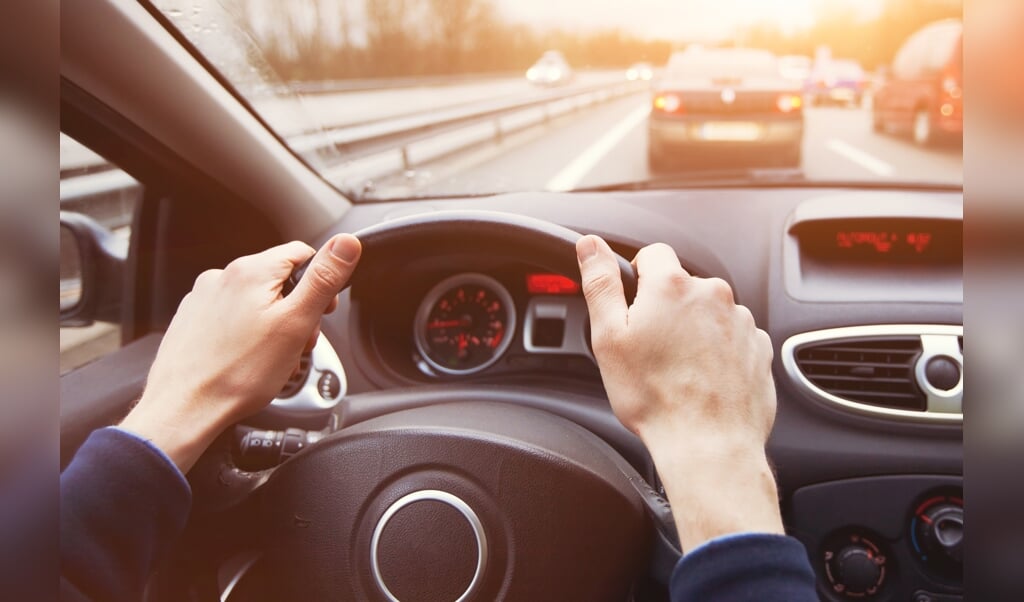 traffic jam, driving car on highway, close up of hands on steering wheel in sunny day ( beeld Getty Images/iStockphoto)