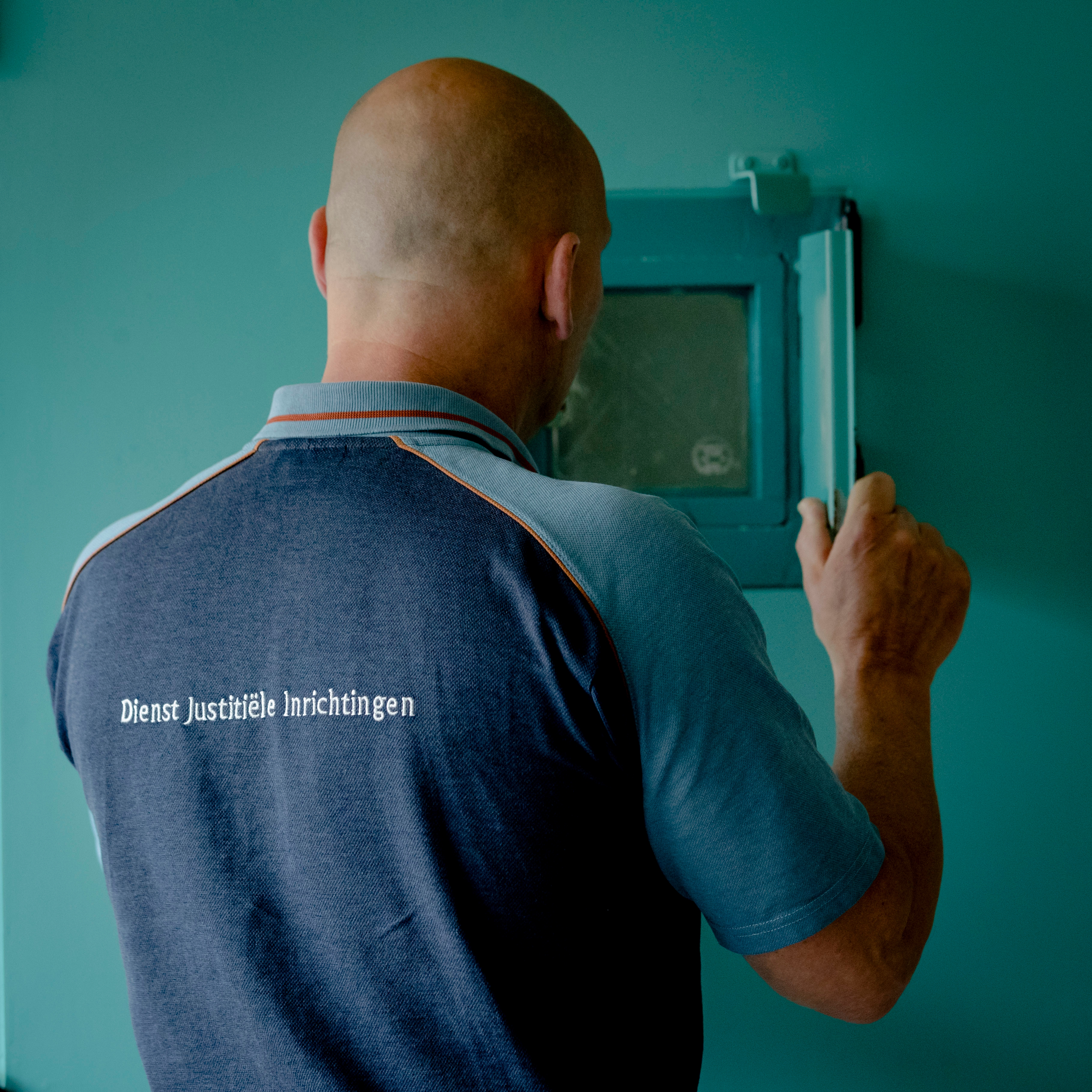 <p>Een medewerker van de gevangenis in Vught kijkt door een celluikje.</p>