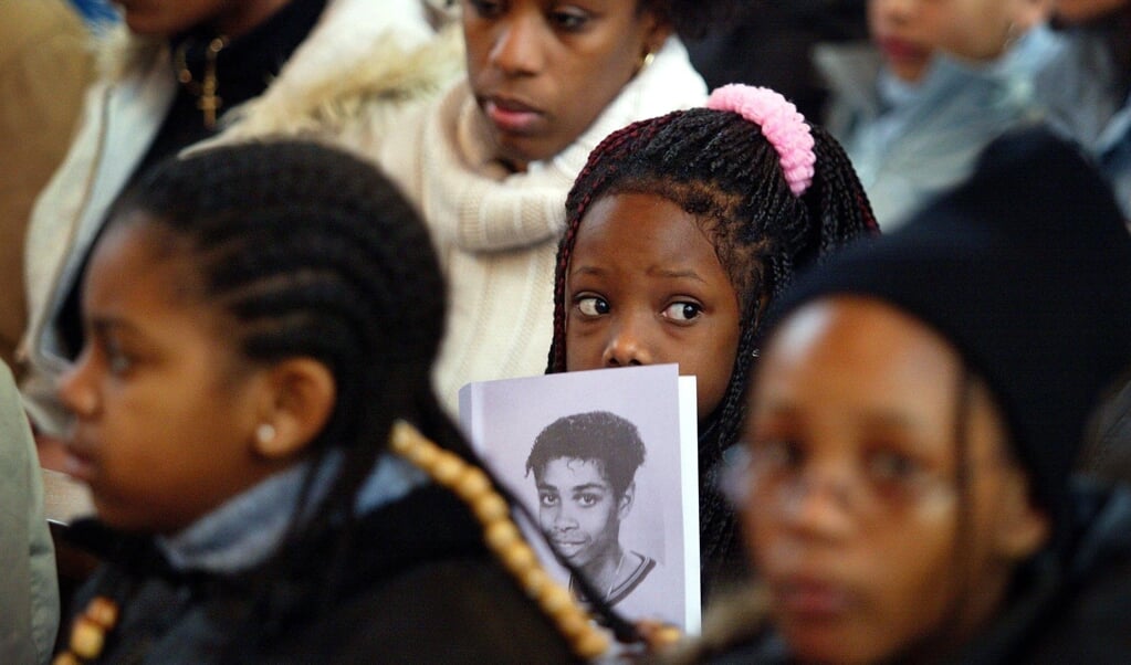 Tijdens een herdenkingsbijeenkomst houdt een meisje een foto van de vermoorde Sedar Soares vast. (beeld anp / Robert Vos)