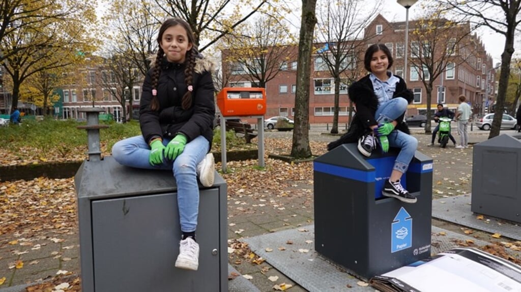De 10-jarige Lara en de 11-jarige Inaya helpen wijkconciërge Leon van der Schelling met het opruimen van zwerfafval in hun wijk. (beeld rtv rijnmond)
