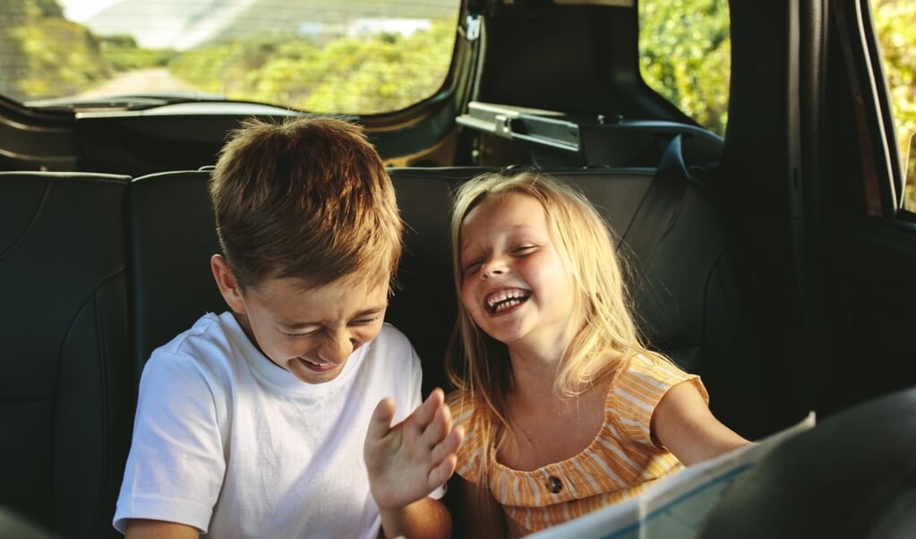 Small boy and girl sitting on backseat of car looking at map and smiling. Kids traveling in a car on roadtrip playing with a map. (Small boy and girl sitting on backseat of car looking at map and smiling. Kids traveling in a car on roadtrip playing wi (beeld istock)