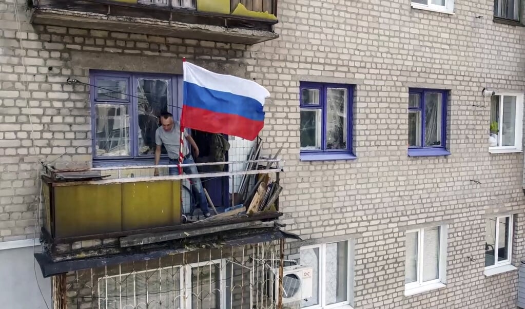 2022-07-04 15:26:09 epa10051474 A still image taken from a handout video provided by the Russian Defence Ministry press service shows a local man flying the Russian flag on his balcony in Lysychansk, Luhansk region, Ukraine, 04 July 2022. Russian Defense Minister Shoigu on 04 July 2022 reported to Russian President Putin that the Russian Armed Forces and the People's Militia of the self-proclaimed Luhansk People's Republic (LPR) established full control over the territories of the self-proclaimed LPR within the administrative boundaries of the Luhansk region. On 24 February 2022 Russian troops entered the Ukrainian territory in what the Russian president declared a 'Special Military Operation', starting an armed conflict that has provoked destruction and a humanitarian crisis.  EPA/RUSSIAN DEFENCE MINISTRY PRESS S  HANDOUT EDITORIAL USE ONLY/NO SALES  (beeld Epa/russian Defence Ministry Press s Handout Editorial use Only/no Sales)