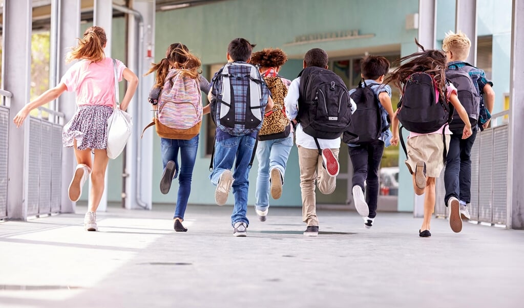 Group of elementary school kids running at school, back view