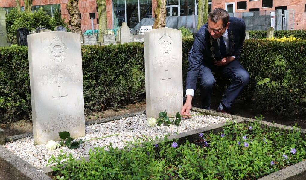 Burgemeester Offinga legt een witte roos op het graf van een omgekomen bemanningslid van een geallieerde bommenwerper.