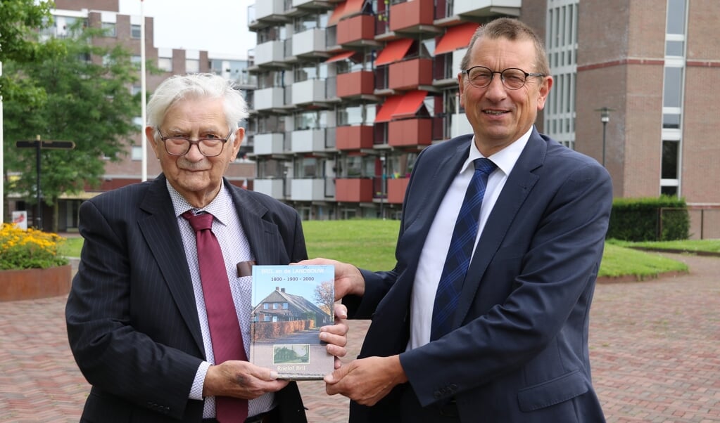 Roelof Bril (links) overhandigt het eerste exemplaar van zijn boek aan burgemeester Maarten Offinga.