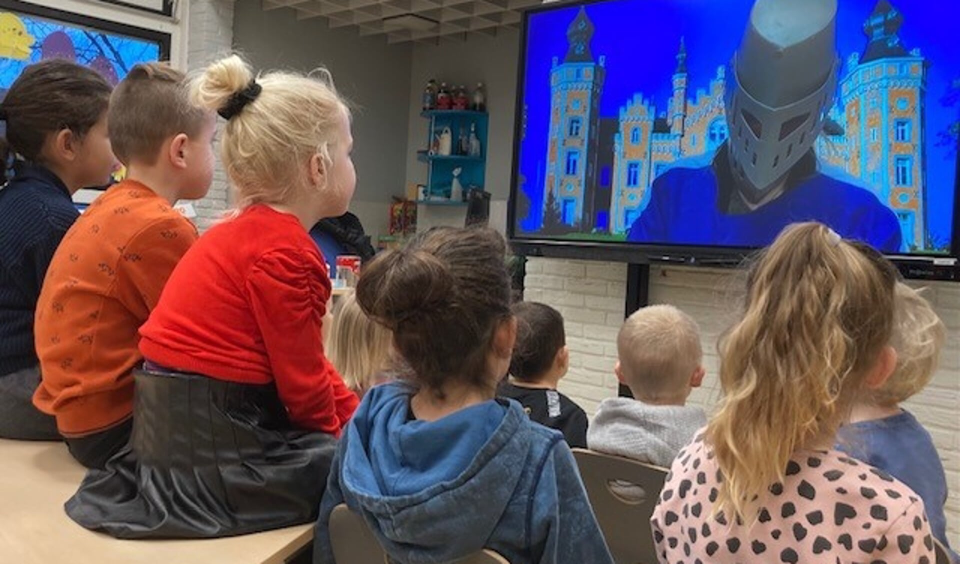 De kinderen keken en luisterden met aandacht naar de Masked reader, die zich via een groot scherm presenteerde. 