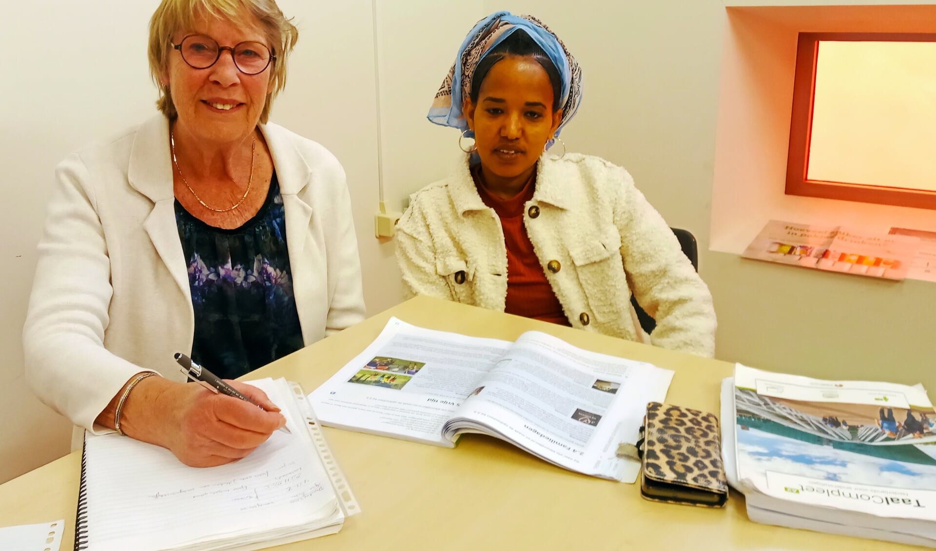 Taalcoach Geja helpt Brkti uit Eritrea met de theorie voor het inburgeringsexamen.