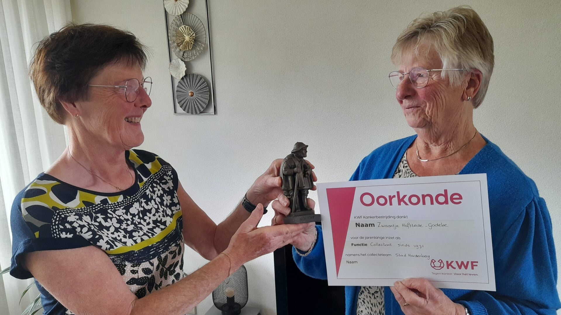 KWF wijkhoofd Lies van Noort overhandigde de oorkonde en het tinnen beeldje aan KWF jubilaris Mevrouw Hofstede-Godeke.