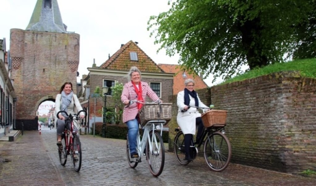 Wethouders Christianne van der Wal, José Oosthoek en Doret Tigchelaar (van links naar rechts) presenteren het boekje op de fiets.