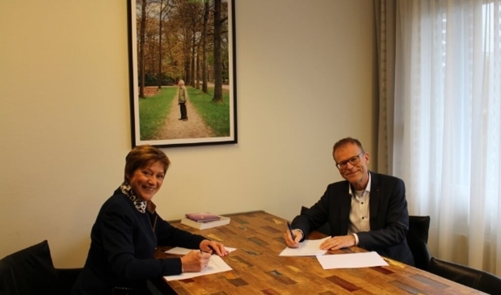 De voorzitter van de cliëntenraad, Lyda Sneevliet, en de bestuurder van Zorgverlening Het Baken, Wilfred Juurlink, ondertekenen de samenwerkingsovereenkomst