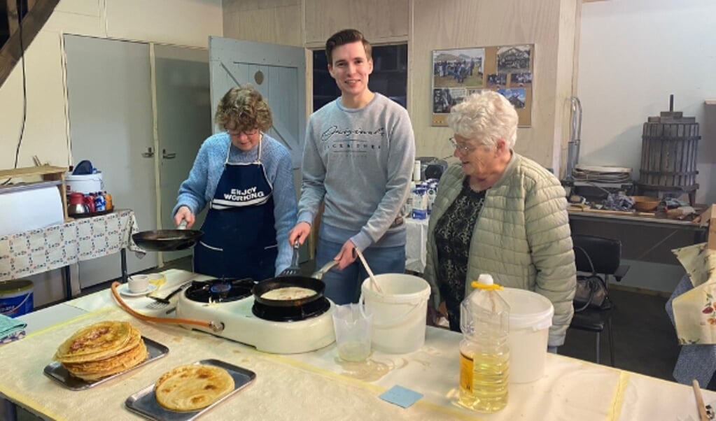 Laurens van Oene (nr. 2 VVD Oldebroek) helpt twee vrijwilligers van het Boerderijmuseum bij pannenkoeken bakken