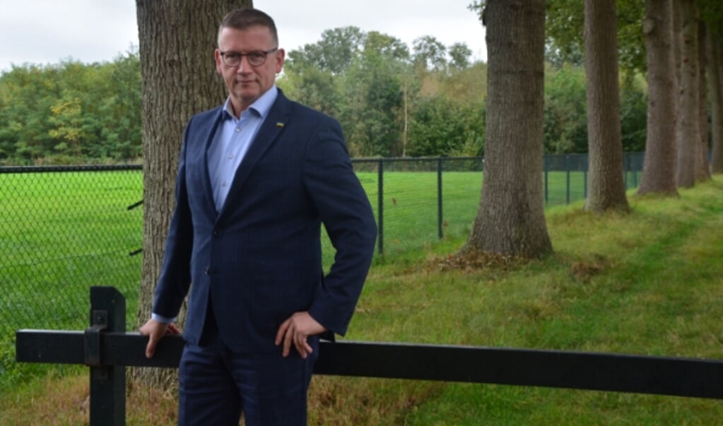 Gedeputeerde Zoet in een natuurlijke omgeving met wei, omheining en een hek. Foto: Dick van der Veen