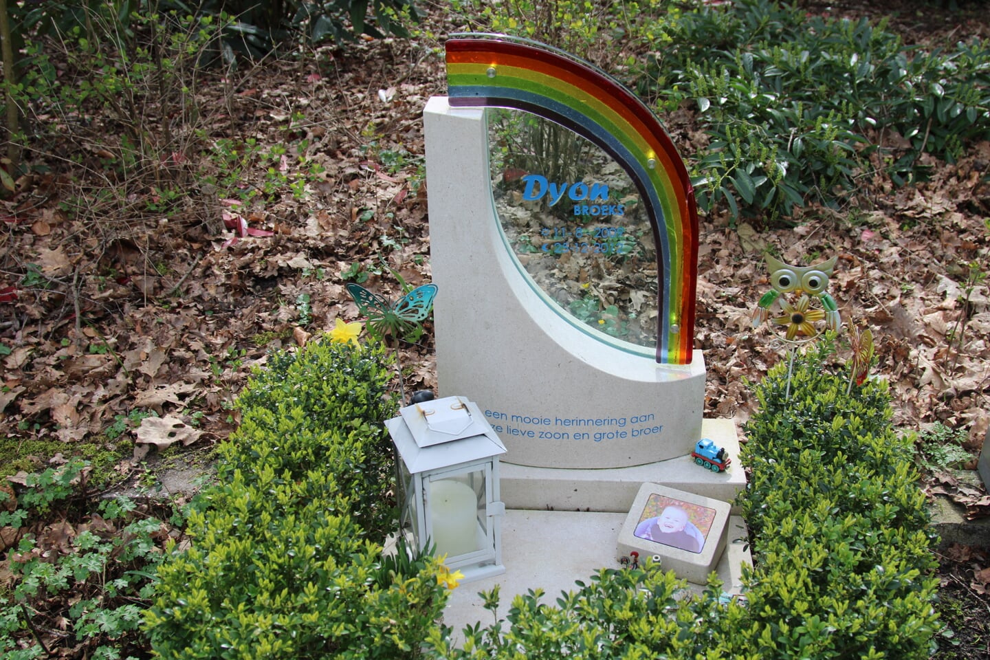  De grafsteen heeft bewust de afbeelding van een regenboog. 