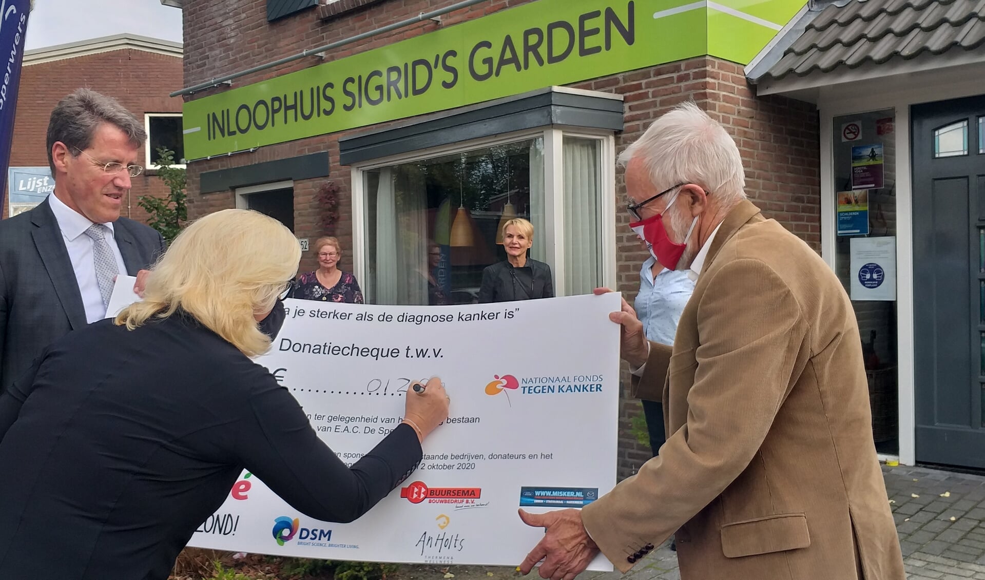 Jannie Vos van De Sperwers vult het chequebedrag in. Onder meer burgemeester Van Oosterhout kijkt toe (foto Bennie Wolbers).