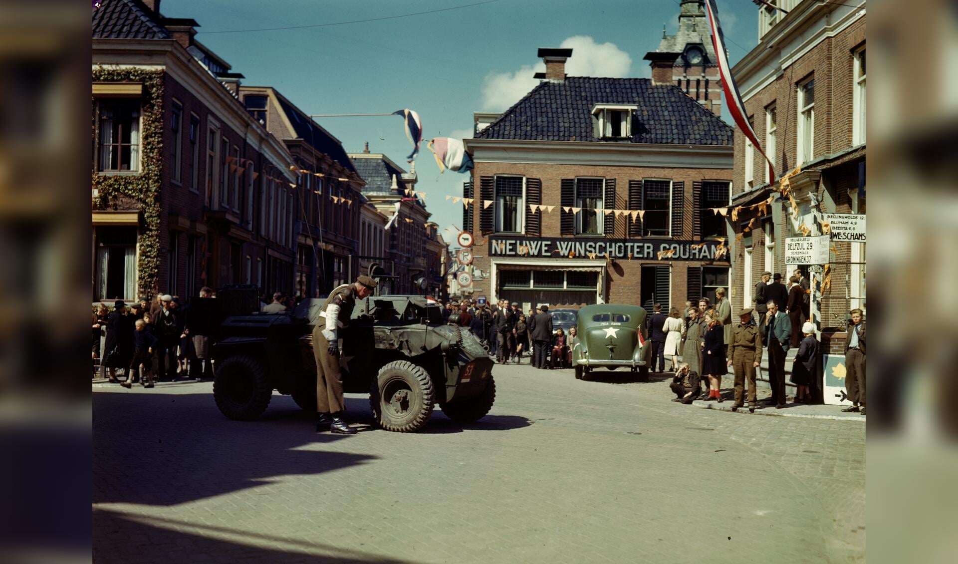 Canadese militairen en feestvierders in de Langestraat in Winschoten, voorjaar 1945. Fotograaf onbekend, collectie National Archives of Canada.