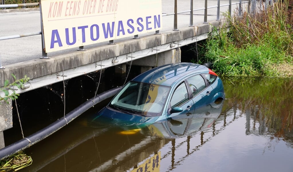 De auto in het kanaal, onder het bord waarop wordt opgeroepen tot autowassen (foto Van Oost Media).