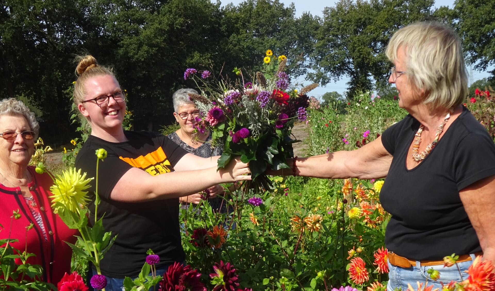 Jolien Hendriks ontvangt de bloemen uit handen van Liesbeth Visser. Verder op de foto oma Sok-Prins en Gea Koning, eigenaar van de bloemenpluktuin (foto Bouke Oudega).